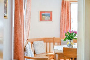A room with a wooden bench, a table with a vase of flowers, and a framed picture on the wall.
