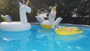 Ein Swimmingpool mit aufblasbaren Einhorn-Schwimmtieren und einem blauen Ball.