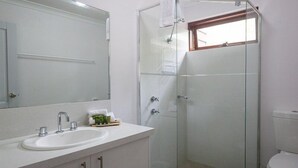 A bathroom with a glass shower enclosure, a sink with a mirror, and a toilet. - Cozy Studio Chalet perfect for couples and a veranda overlooking the bushland (Margaret River)