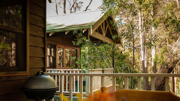 A wooden cabin with a balcony, surrounded by trees.