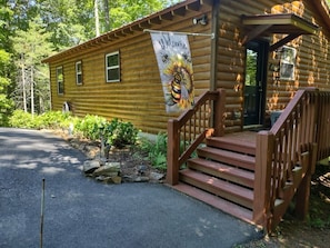 Une cabane en bois avec une banderole « Bienvenue », un escalier en bois et une allée pavée.