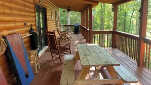 Eine Holzterrasse mit Picknicktischen und -stühlen, umgeben von einer Holzhütte.