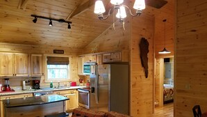 Ein Interieur einer Holzhütte mit Küche, Essbereich und einer gemütlichen Sitzecke.