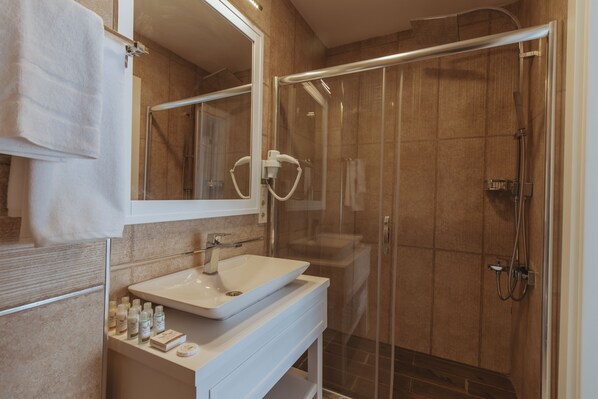 A modern bathroom with a glass-enclosed shower, a white sink, and a mirror.