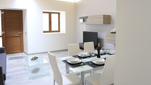 A modern kitchen with wooden cabinetry, a dining area with white chairs, and a small window. - Individual house, with 3 bedrooms, 3 bathrooms, living room, kitchen, garden (La Orotava)