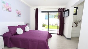 A bedroom with a large bed, a TV mounted on the wall, and a sliding glass door leading to a balcony. - Individual house, with 3 bedrooms, 3 bathrooms, living room, kitchen, garden (La Orotava)