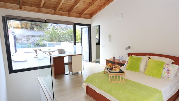 A bedroom with a bed, a desk, and a balcony. - Individual house, with 3 bedrooms, 3 bathrooms, living room, kitchen, garden (La Orotava)