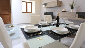 A dining area with a glass table set for six, white chairs, and a bottle of champagne. - Individual house, with 3 bedrooms, 3 bathrooms, living room, kitchen, garden (La Orotava)