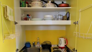 Una cocina compacta con gabinetes amarillos, un fregadero y diferentes utensilios de cocina.
