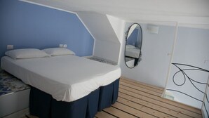 A bedroom with a bed, a mirror, and a wooden floor. - Casa Niccolò 5 (max 4 pp) (Napoli)