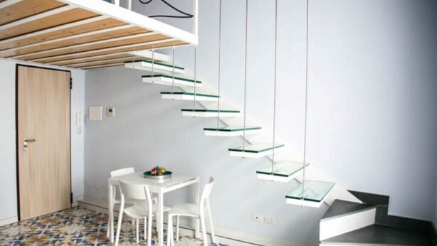 A modern interior with a spiral staircase, a dining area with a table and chairs, and a patterned floor. - Casa Niccolò 5 (max 4 pp) (Napoli)