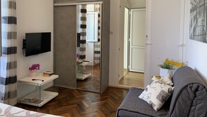 Ein modernes Wohnzimmer mit grauem Sofa, Flachbildfernseher, Glastisch und einer Schiebetürenausstattung.