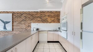 Una cocina moderna con armarios blancos, una pared de ladrillo decorativa y un lavavajillas.