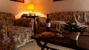 A living room with floral-patterned sofas, a table with a bottle of wine, a glass, and a small potted plant.