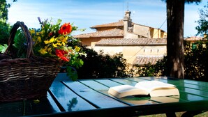 A green table with an open book and a wicker basket with flowers.