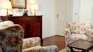 A living room with floral-patterned chairs, a wooden coffee table, and a cabinet with decorative items.