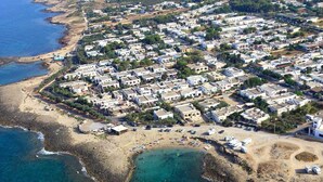 An aerial view of a coastal residential area with houses, a beach, and a rocky shoreline. - Simona holiday home. (TAVIANO)