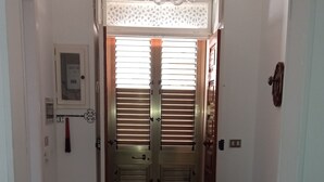 A hallway with a tiled floor, a wooden bench, and a door with a decorative glass ceiling. - Simona holiday home. (TAVIANO)