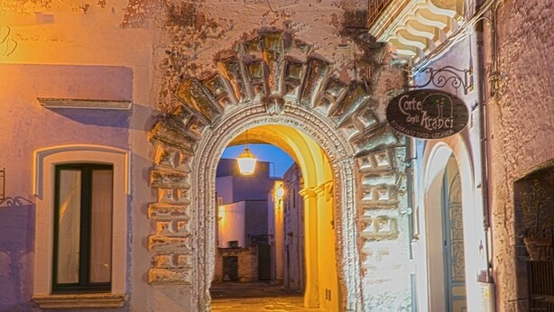 An arched street entrance with a sign for "Corte del Cracco" and a well-lit interior. - Simona holiday home. (TAVIANO)