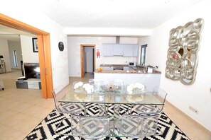 Relax in this stylish living area with a glass dining table and comfortable seating, surrounded by a patterned rug.