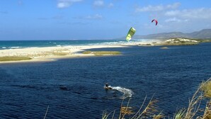 A beach with a person windsurfing, a kiteboarder, and a parasail in the background. - Independent beachfront accommodation. (valledoria)