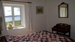 A bedroom with a bed, a window with curtains, a dresser, and a painting on the wall. - Beautiful house with garden that runs down to the sea (Cashel)
