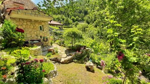 A stone building with a garden featuring various plants and flowers. - Holiday house with private pool in a quiet location (Podašpilje)