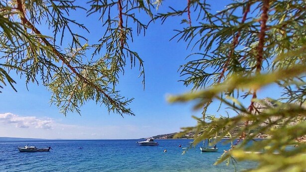 A beach with clear shallow waters, boats, and a distant shoreline. - Holiday house with private pool in a quiet location (Podašpilje)