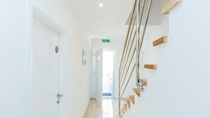 A hallway with a white door, a staircase with wooden steps, and a green exit sign. - Guest House Nikolina - Double Room(6) (Dubrovnik)