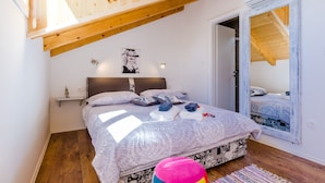 A bedroom with a sloped ceiling, a bed with a patterned bedspread, a bedside table, a small shelf, and a mirror on the wall. - Guest House Nikolina - Double Room(6) (Dubrovnik)