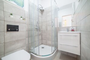 A modern bathroom with a glass-enclosed shower, a white toilet, and a vanity with a mirror. - Automatic Apartment - Jablonowskich street (Stare Miasto)