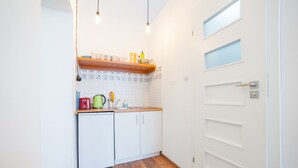 Una cocina compacta con armarios blancos, encimera de madera y un refrigerador pequeño.