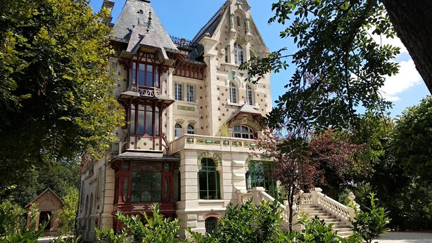 A historic building with a steeply pitched roof, ornate windows, and a prominent staircase leading to the entrance. - Villa Alecya (Sainte-Catherine-de-Fierbois)