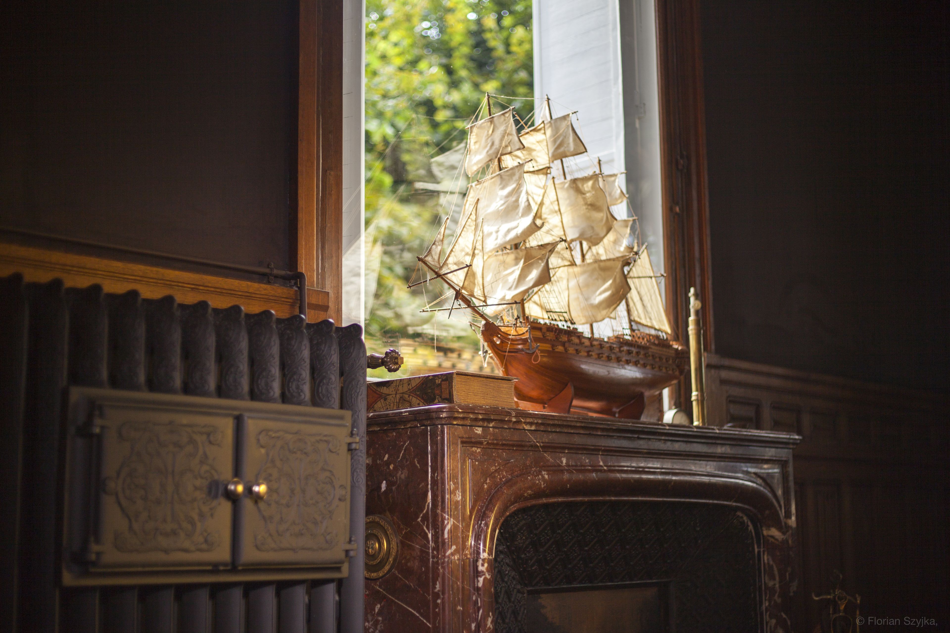 A model ship on a wooden cabinet near a window.