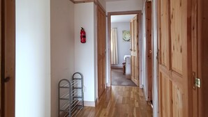 Un couloir doté d’un plancher en bois, d’un extincteur et d’une étagère en métal.