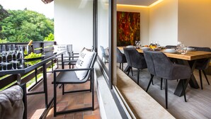 A dining area with a long table and chairs, a balcony with a view of greenery, and a sign with the text "SAVE JUICE". - "Waldblick" - 90 m² oasis of tranquility: Modern design & 2 bathrooms (Bad Sachsa)