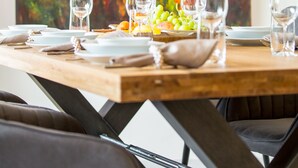 A dining table set with wine glasses, plates, and a centerpiece of grapes and bread, with a vibrant abstract painting in the background. - "Waldblick" - 90 m² oasis of tranquility: Modern design & 2 bathrooms (Bad Sachsa)