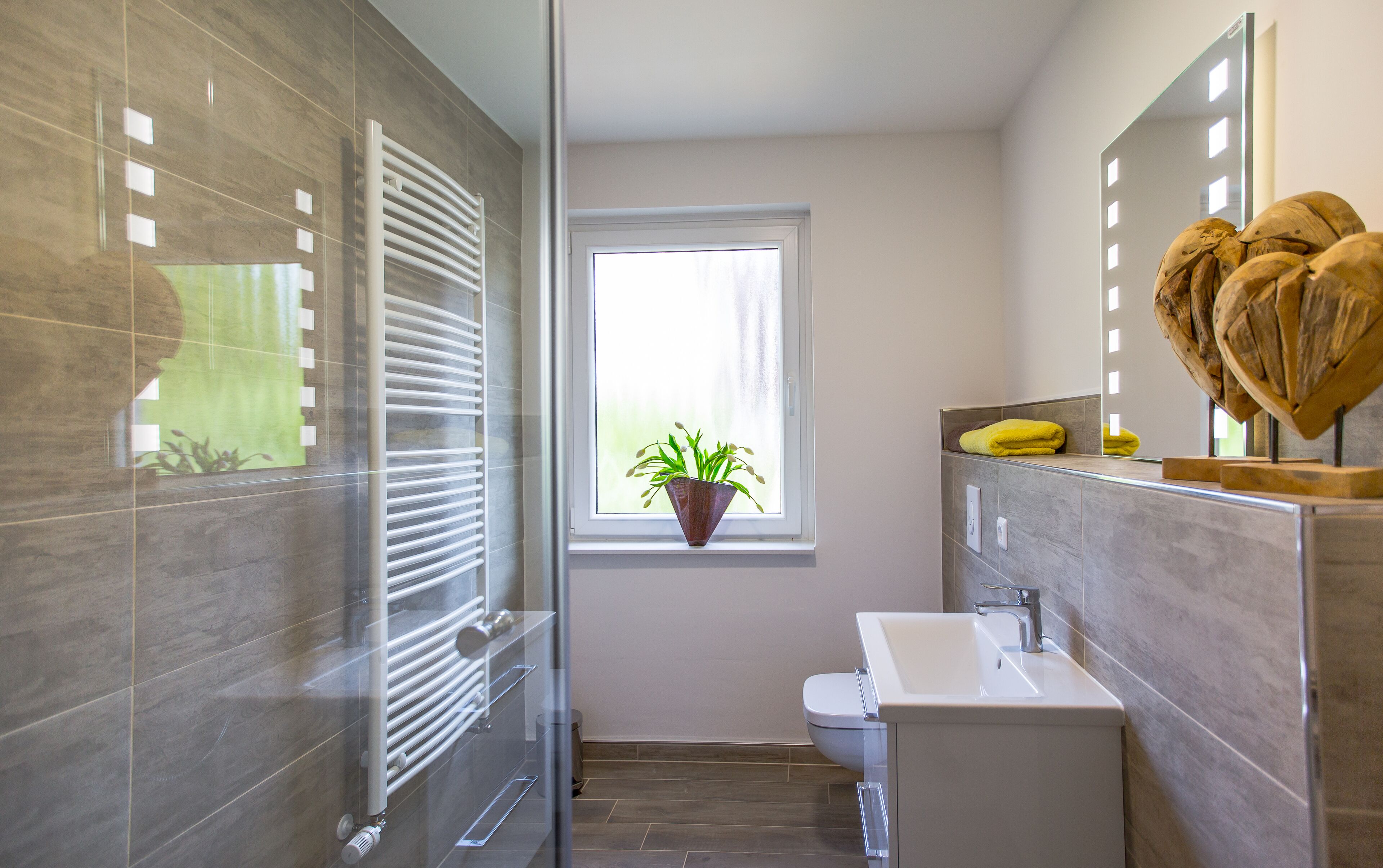 A modern bathroom with a glass shower enclosure, a toilet, and a sink with a mirror above it.