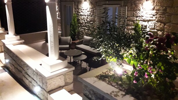 Ein möblierter Terrassenbereich mit Steinmauern und Pflanzkübeln.