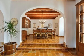 A dining area with a wooden table and chairs, a chandelier, and a clock on the wall.