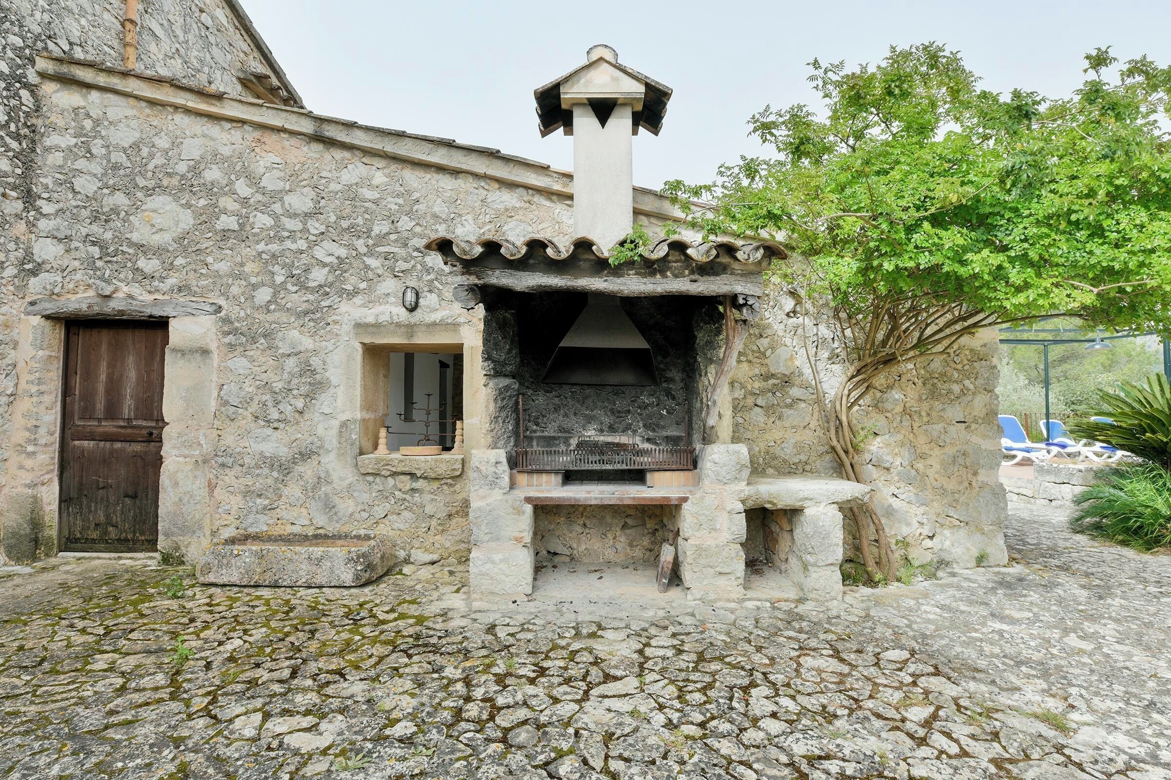 Un bâtiment en pierre avec une cheminée, une porte en bois et un banc.