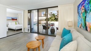 A modern hotel room with a balcony, a bed, a sofa, and a painting.