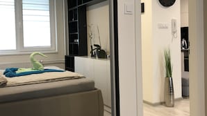 Une chambre à coucher moderne, dotée d’un lit, de tables de chevet, d’une grande fenêtre et d’une armoire intégrée.