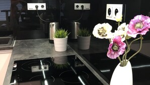 Une cuisine moderne avec des plans de travail noirs, des appareils en acier inoxydable et un vase blanc orné de fleurs.