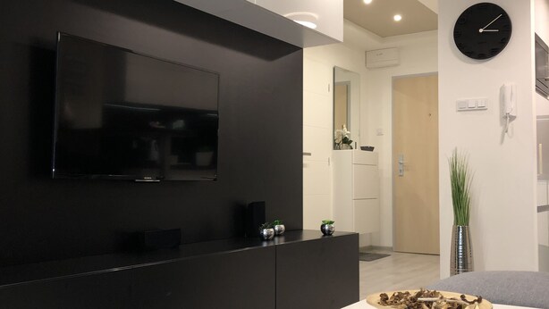 Une cuisine moderne avec un plan de travail noir, une table blanche et une horloge au mur.