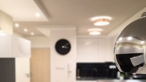 Une cuisine moderne avec une horloge, un coin repas et un téléviseur.