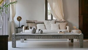 Een minimalistische slaapkamer met een bed, nachtkastje en een decoratieve bank.