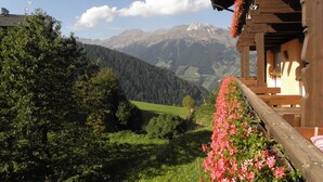 A wooden chalet with a balcony overlooking a mountainous landscape. - Sporthotel Kalcherhof (Racines)