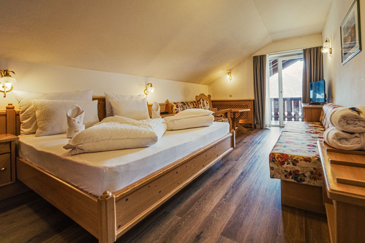 Une chambre d’hôtel avec un grand lit, un petit canapé, un bureau et une télévision.