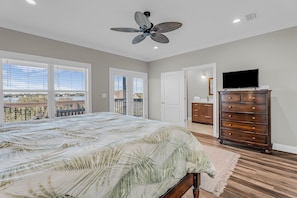 Un dormitorio con cama, cómoda, ventilador de techo y televisión.